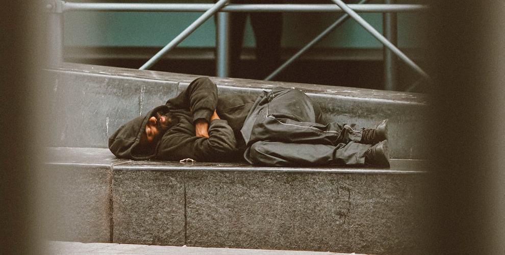 Ein Obdachloser schläft auf der Straße.