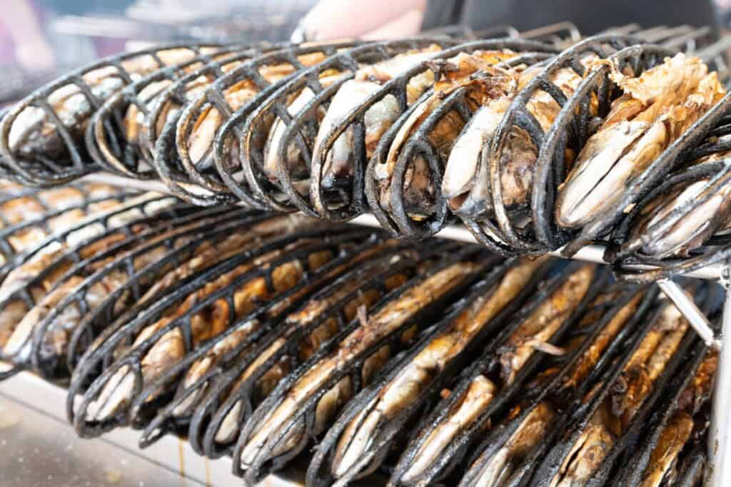Frisch gegrillte Steckerlfische in Metallhalterungen auf einem Grillstand beim Herbstvolksfest.