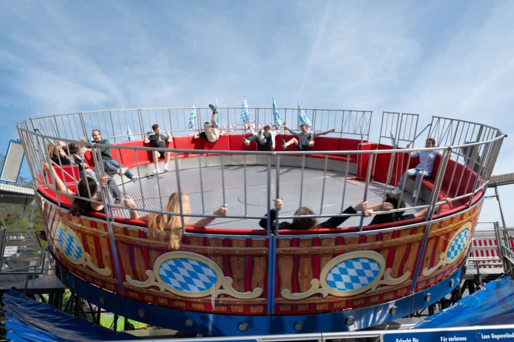 Rundes Karussell mit rotem Innenraum, auf dem Menschen herumwirbeln – typische Jahrmarktszene in Nürnberg.